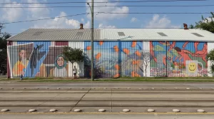 Three colorful murals face a busy street in downtown Houston.